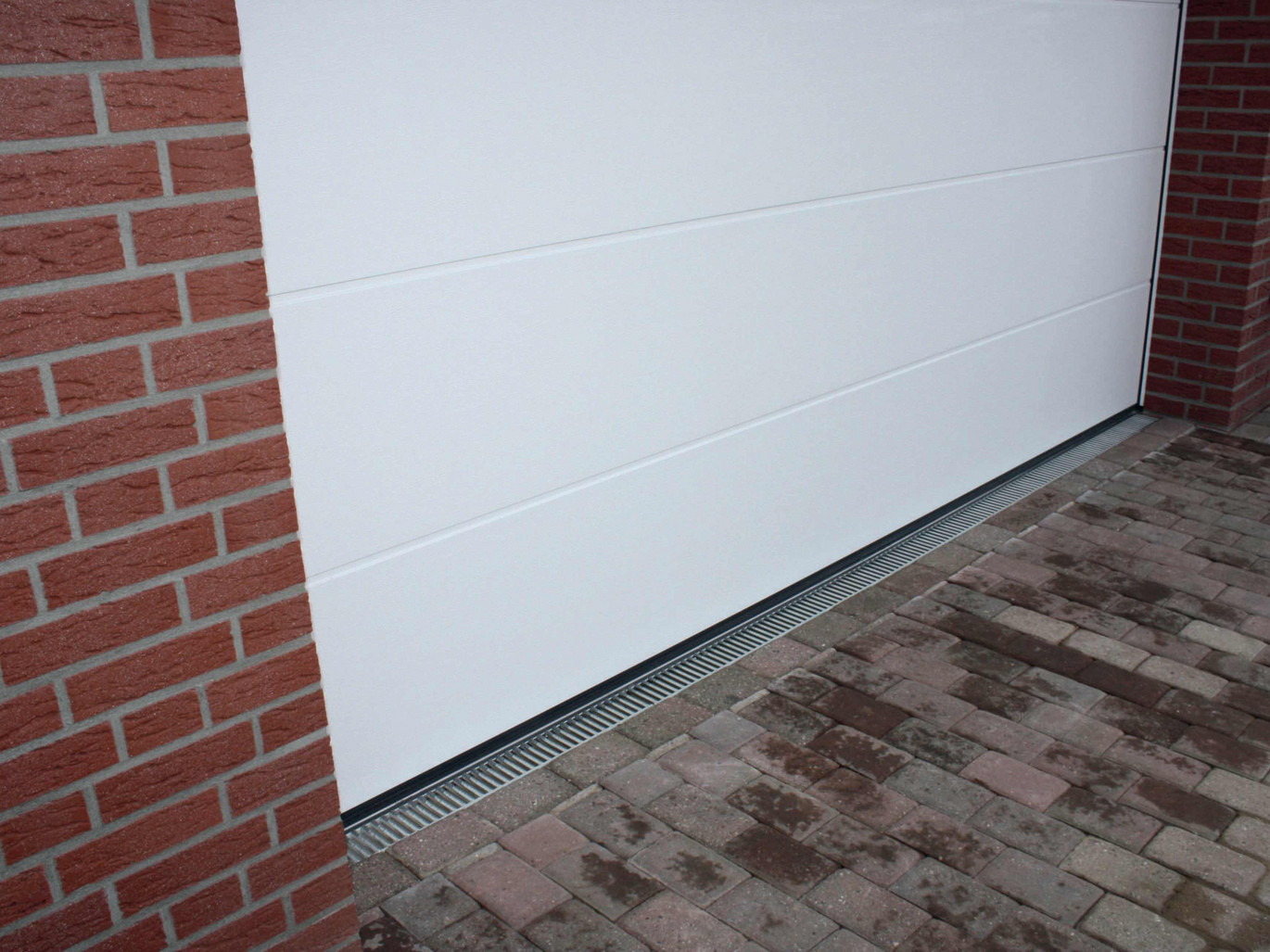 Der fertiggestellte Rinnenstrang in der Pflasterfläche vor der Garage entlastet die Schwelle und verhindert aufspritzendes Wasser im Torbereich