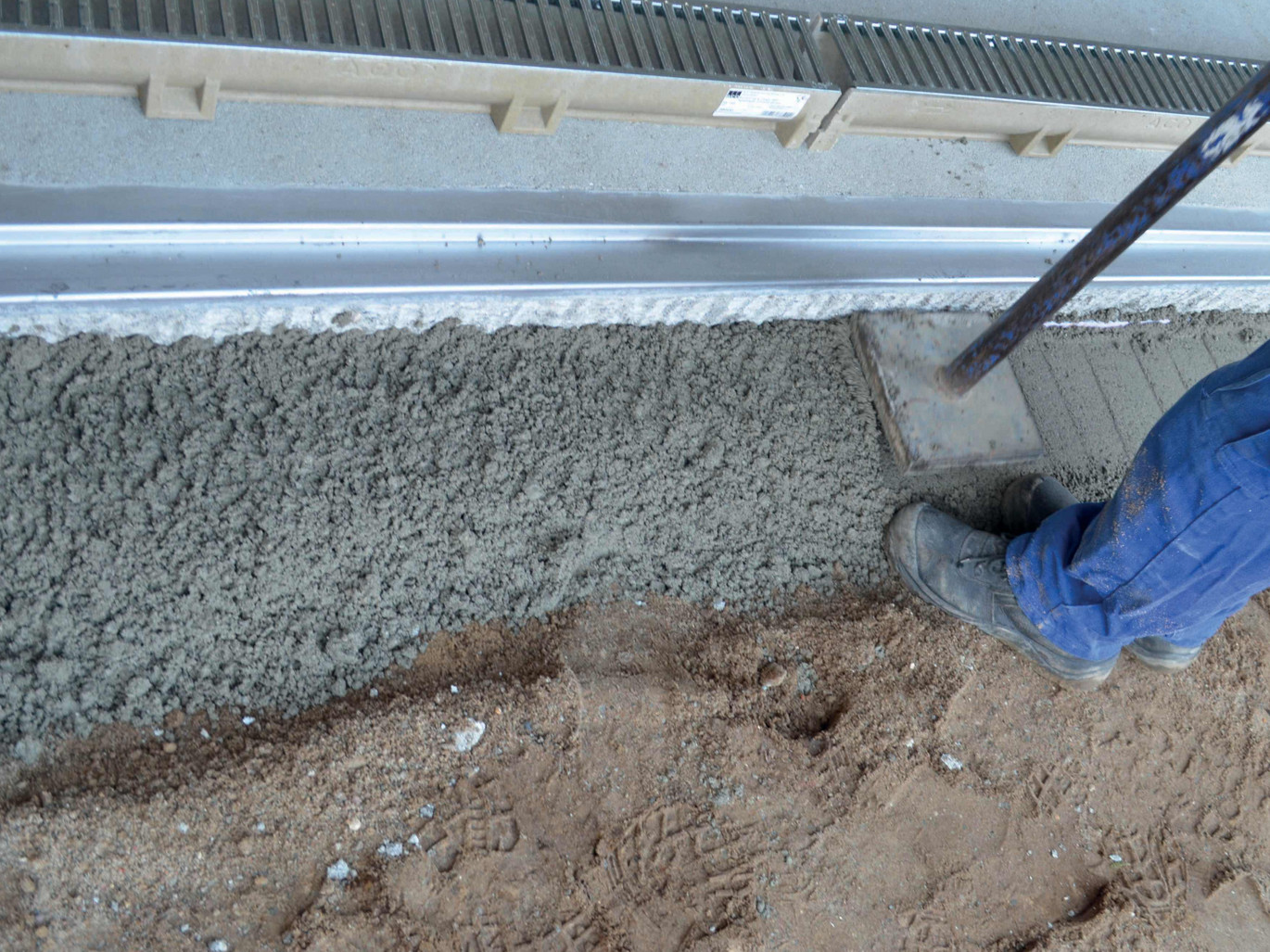 Verdichten des Rinnenfundamentes. Vorbereiten des Ablaufes für KG-Rohr DN/OD 110