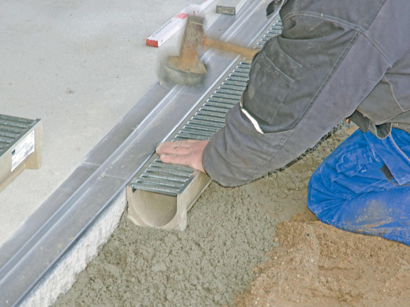 Ansetzen des Rinnenkörpers an den Einlaufkasten. Ausrichten des Rinnenstrangs. Die 2 cm Garagenschwelle ist so ausgeführt, dass das Tor zwischen Schelle und Rinne schließt