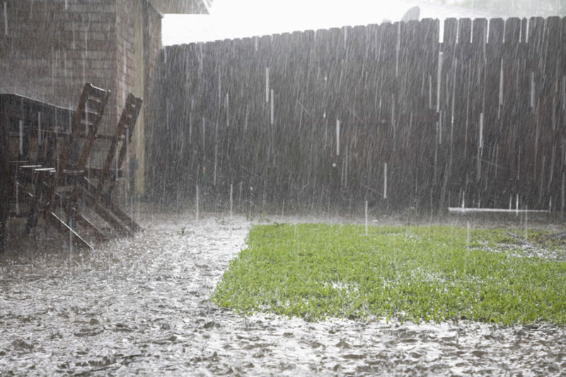Regenbild - Bei einem Starkregen bleibt auf Terrasse und Rasenfläche das Wasser an der Oberfläche