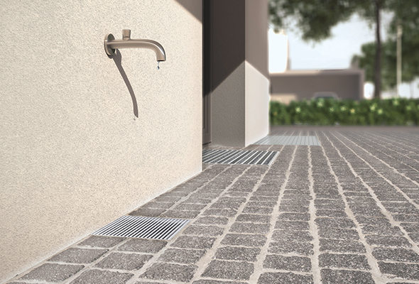Wasserhahn an einer Hauswand mit Hofablauf als Wasserfang