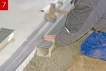 Ansetzen des Rinnenkörpers an den Einlaufkasten. Ausrichten des Rinnenstrangs. Die 2 cm Garagenschwelle ist so ausgeführt, dass das Tor zwischen Schelle und Rinne schließt